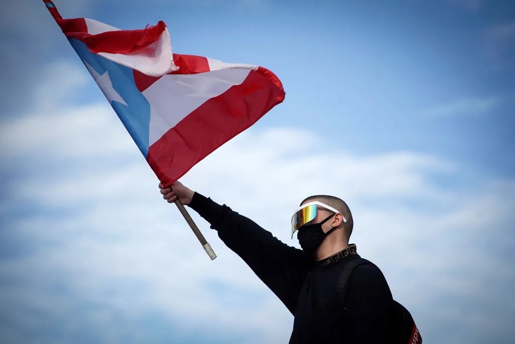 Bad Bunny holding the Puerto Rican flag during a protest in Puerto Rico in 2019. Photo by Eric Rojas for AFP via Getty Images.