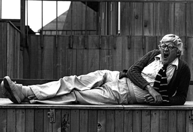 David Hockney, circa 1970s, wearing a checkered suit and signature round glasses. A pioneer of British Pop Art, Hockney's personal style became as recognizable as his paintings.  Image Credit: Photographer unknown. Image sourced from Men's Fashion Magazin